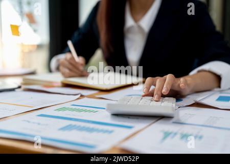 Primo piano bilancio di pianificazione della donna, utilizzando calcolatore e laptop, lettura di documenti, giovane donna controllo finanze, conteggio fatture o tasse, online Foto Stock