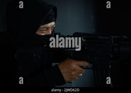 Ritratto di terrorista in passamontagna holding fucile su sfondo bianco  Foto stock - Alamy