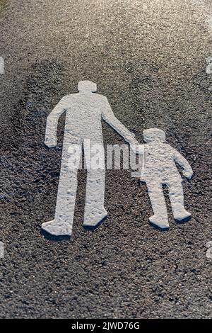 Strada asfaltata con segnaletica pedonale bianca dipinta su di essa, cartello segnaletico sul marciapiede Foto Stock