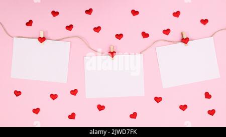 Carte romantiche con spazio di copia appeso su corda su sfondo rosa pastello con cuori . Appartamento Lay San Valentino Foto Stock