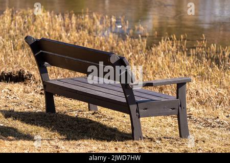 Una vecchia panca in legno sulla riva del lago Foto Stock