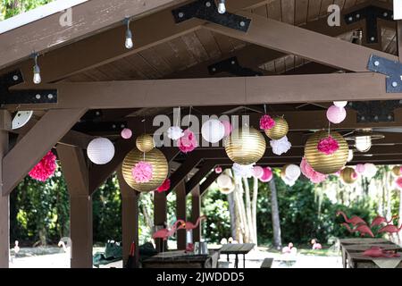 lanterne d'oro e di carta rosa appese in un parco locale per una festa di compleanno Foto Stock