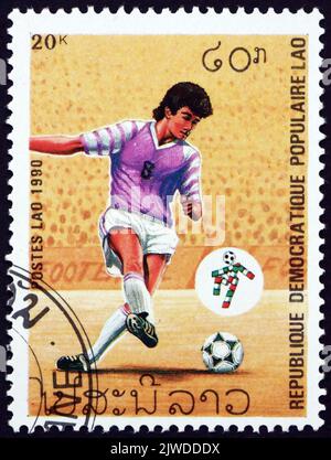 LAOS - CIRCA 1990: Un francobollo stampato in Laos mostra il giocatore di calcio in azione, Campionati Mondiali di Calcio 1990, Italia, circa 1990 Foto Stock