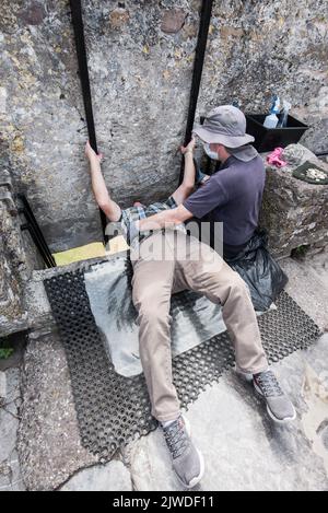 Baciare la pietra di Blarney, un blocco di pietra calcarea carbonifera costruito nei merlamenti a Blarney Castle and Gardens, Blarney, Co. Cork, Foto Stock