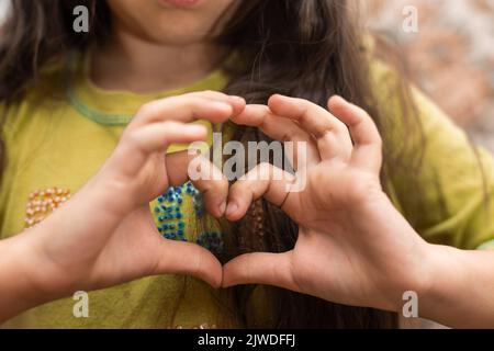 Foto di ragazza divertente allegra e allegra casual che mostra il segno di forma del cuore con le dita sopra la testa Foto Stock