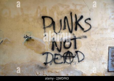 Punks non Dead Anarchy o slogan anarchico o Graffiti sulla vecchia parete degradata o facciata danneggiata Foto Stock