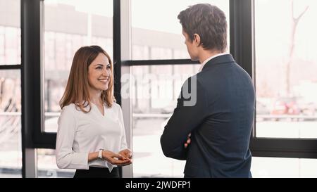 uomo d'affari che ascolta la donna sorridente che parla durante l'intervista di lavoro, immagine di riserva Foto Stock