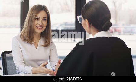 donna sorridente che parla con la donna d'affari brunette durante l'intervista di lavoro, immagine di riserva Foto Stock