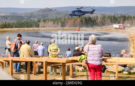 Braunlage, Germania. 05th Set, 2022. Un elicottero della polizia federale prende l'acqua da un lago sul Wurmberg, mentre numerosi escursionisti e spettatori guardano gli sforzi antincendio. Centinaia di addetti alle emergenze combattono un grande incendio boschivo nei monti Harz. Credit: Julian Stratenschulte/dpa/Alamy Live News Foto Stock