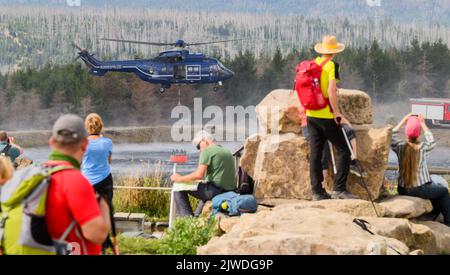 Braunlage, Germania. 05th Set, 2022. Un elicottero della polizia federale prende l'acqua da un lago sul Wurmberg, mentre numerosi escursionisti e spettatori guardano gli sforzi antincendio. Centinaia di addetti alle emergenze combattono un grande incendio boschivo nei monti Harz. Credit: Julian Stratenschulte/dpa/Alamy Live News Foto Stock