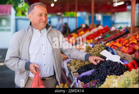 Uomo di mezza età che acquista frutti Foto Stock