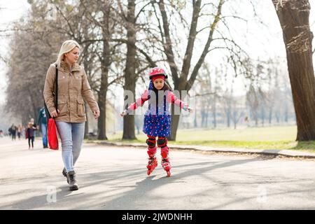 Madre e sua figlia che indossano pattini a rotelle nel parco Foto Stock