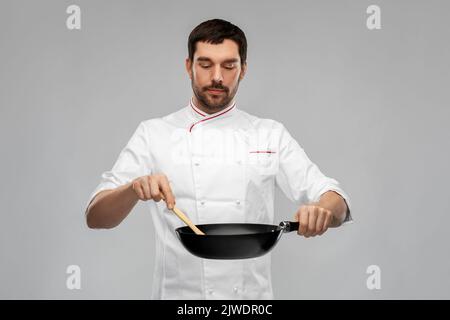 chef maschile in giacca cucina su padella Foto Stock