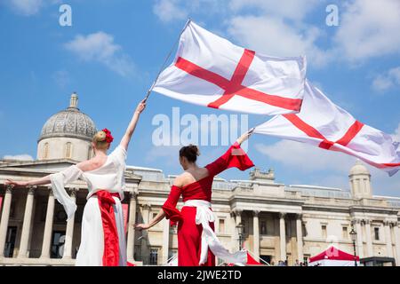 La gente guarda spettacoli acrobatici mentre si riuniscono per le celebrazioni del giorno di San Giorgio a Trafalgar Square, nel centro di Londra. Foto Stock