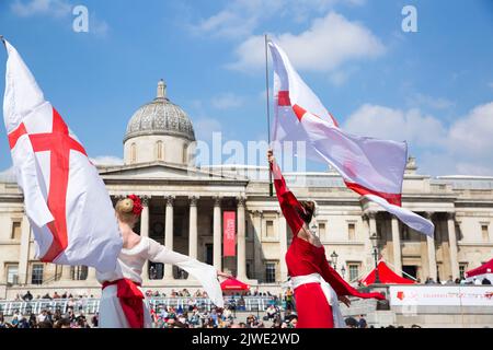 La gente guarda spettacoli acrobatici mentre si riuniscono per le celebrazioni del giorno di San Giorgio a Trafalgar Square, nel centro di Londra. Foto Stock