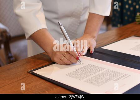 La sposa firma i documenti di registrazione del matrimonio Foto Stock