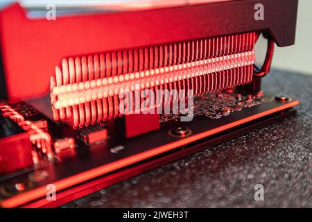 Primo piano del sistema di raffreddamento della scheda grafica o video GPU con luce rossa, dettagli elettronici dell'hardware del PC, componenti per gamer o attività di estrazione crittografica Foto Stock