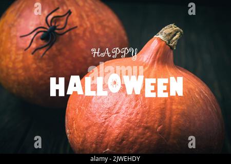 Buon poster di Halloween, zucche e ragno su sfondo scuro. Parola Halloween, testo tipografico e cibo rosso arancio. Design, logo, natura, autunno, festa Foto Stock