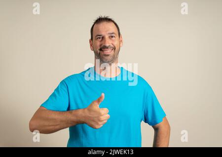 Uomo ispanico adulto sopra lo sfondo isolato facendo i pollici felici in su il gesto con la mano. Approvazione dell'espressione guardando la telecamera che mostra il successo Foto Stock