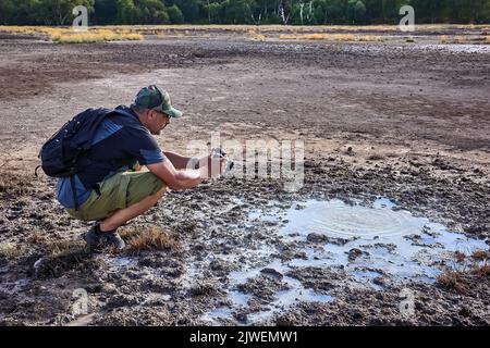 L'escursionista visita la caldera, un piccolo cratere circolare con una palude di acque sulfuree, testimonianza dell'antica presenza di un vulcano. Foto Stock