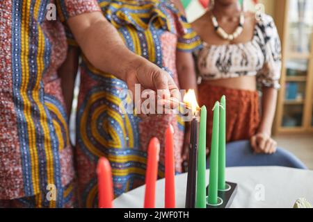 Primo piano della famiglia africana che brucia sette candele per la festa di Kwanzaa per celebrarla a casa Foto Stock