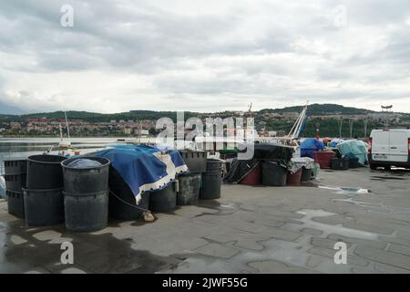 Secchi e scatole in plastica nera riempiti di reti da pesca pronti per il carico in imbarcazioni ormeggiate nel porto di pesca di Capodistria, Slovenia. Foto Stock