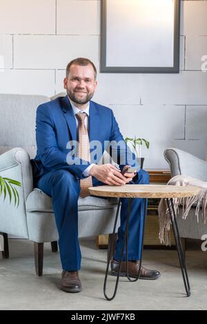 Sorridente uomo d'affari di mezza età freelancer utilizzando il telefono cellulare controllare i feed dei social media o messaggi di chat mentre si siede in caffetteria. Comunicazioni digitali online Foto Stock