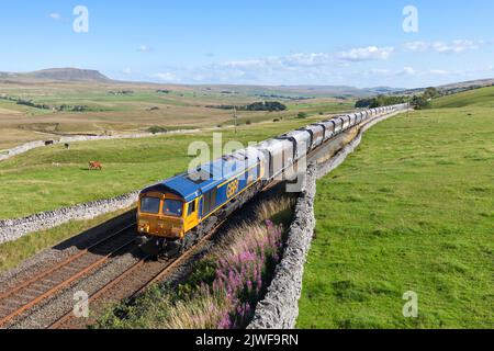GB Raillocomotiva classe 66 a Ribblehead, stabilirsi a Carlisle ferrovia con un treno merci che trasporta aggregati dalla cava di Arcow vicino a Settle Foto Stock