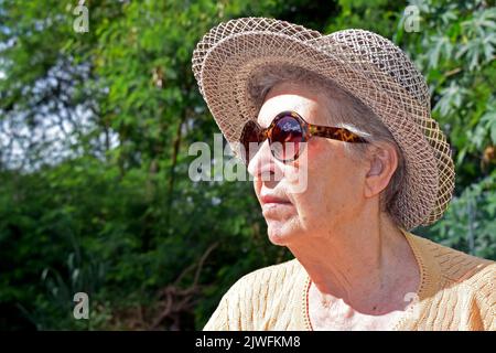 Donna anziana che prende il sole nel parco Foto Stock