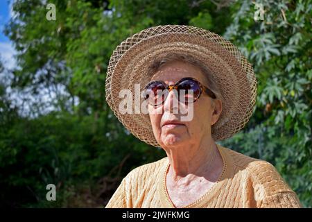 Donna anziana che prende il sole nel parco Foto Stock