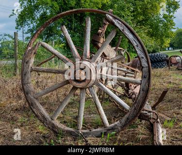 Vecchia ruota del carro arrugginita e spaccata di legno. Foto Stock