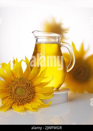 Olio di girasole in un vaso di vetro circondato da fiori. Foto pubblicitaria per la copertina del libretto Foto Stock
