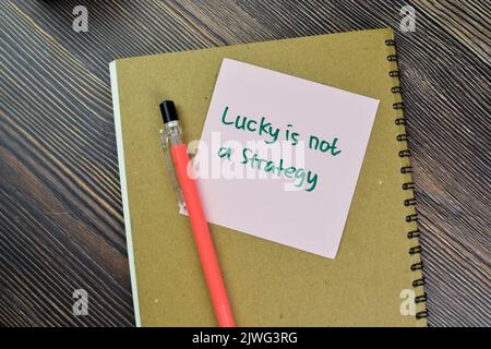 Concetto di Lucky non è una strategia scrivere su note appiccicose isolato su tavola di legno. Foto Stock