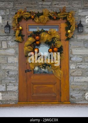 Porta d'ingresso frontale in legno con decorazioni natalizie su una vecchia casa in stile cottage Canadiana del 1750 circa. Foto Stock