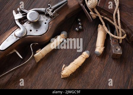 antico muschio di flintlock del xvii secolo con fiasca di polvere e pallottole a led su ponte di legno. Foto Stock