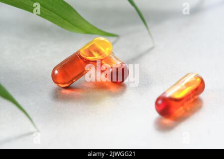 Curcumina in forma liquida. Capsule di erbe, capsule di curcuma alle erbe su fondo neutro con ombra di foglie di palmo. Estratto di medicina di erbe da curcuma Foto Stock