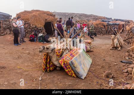 AFAR, ETIOPIA - 26 MARZO 2019: Turisti con cammelli al bordo del cratere del vulcano Erta Ale nella depressione di Afar, Etiopia Foto Stock