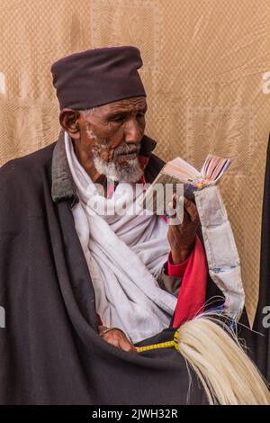 LALIBELA, ETIOPIA - 29 MARZO 2019: Sacerdote cristiano che legge una Bibbia di fronte a Bet Maryam, chiesa di Lalibela, Etiopia Foto Stock