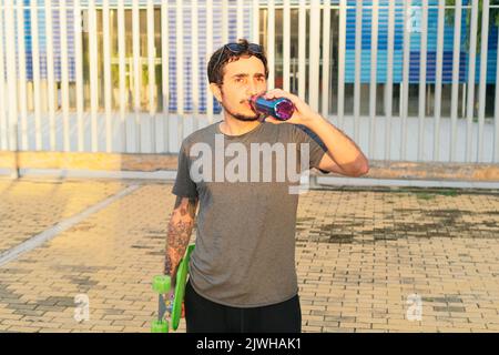 Giovane uomo che beve acqua dopo lo skateboard Foto Stock