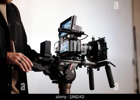 Primo piano del cameraman o del direttore del team di tiro utilizzando stalicam mentre si è in studio e lavorando sulla creazione di spot Foto Stock