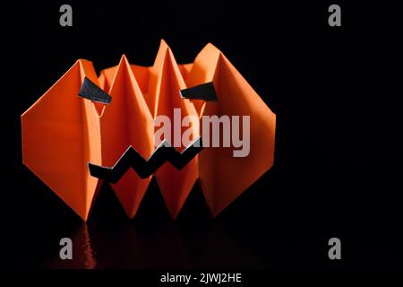 Concetto di Halloween. Carta scary zucca o jack o lanterna su sfondo nero scuro con spazio copia. Foto Stock