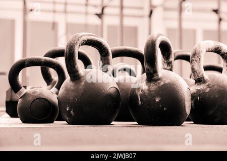 Al piano terra di molti kettlebells pesanti per gli allenamenti funzionali posti sul pavimento in palestra leggera Foto Stock