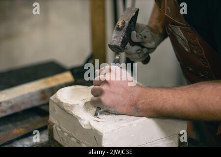 Uomo scultore crea scultura busto gesso uomo donna scultura con martello. Laboratorio di creazione di statue artigianali. Foto Stock