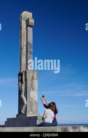 Due ragazze che fanno un selfie nel monumento formato da una croce di granito e la silhouette di una persona aggrappata ad esso, inaugurato nel 1941 per commemorare Foto Stock