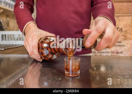 Barista che versa in bicchieri di liquore di ciliegia Ginjinha a Lisbona, Portogallo Foto Stock