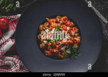 Gustosa e appetitosa pasta italiana classica con salsa di pomodoro, parmigiano e basilico sul piatto Foto Stock