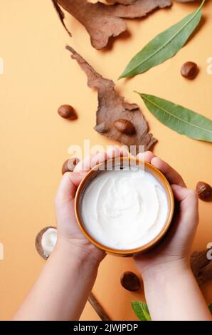 Le mani del bambino che tengono il burro di karitè non raffinato in una ciotola. Foto Stock