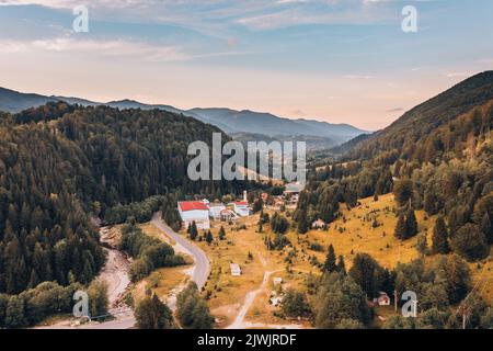 Splendida vista panoramica sulle montagne al tramonto. Piccolo villaggio europeo ai piedi della montagna. Foto Stock