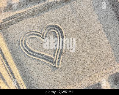 Cuore disegnato sulla sabbia in una cornice, vista dall'alto, primo piano. Spazio di copia. Foto Stock