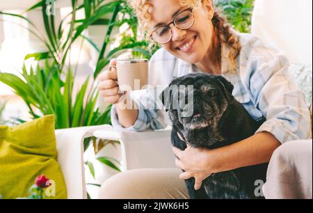 Animale cane migliore amico insieme concetto con felice giovane donna proprietario abbracciare con amore e amicizia il suo adorabile pug nero cucciolo all'aperto a casa in Foto Stock